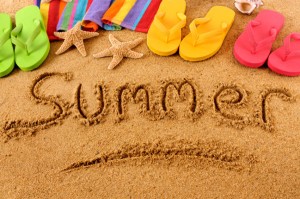 The word Summer written on a sandy beach, with beach towel, starfish and flip flops (studio shot - warm color and directional light are intentional).  Note: extreme wide angle shot with curvature of field and focus on the word Summer.