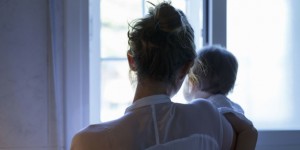 Rear view of mid adult woman and baby daughter looking out of living room window